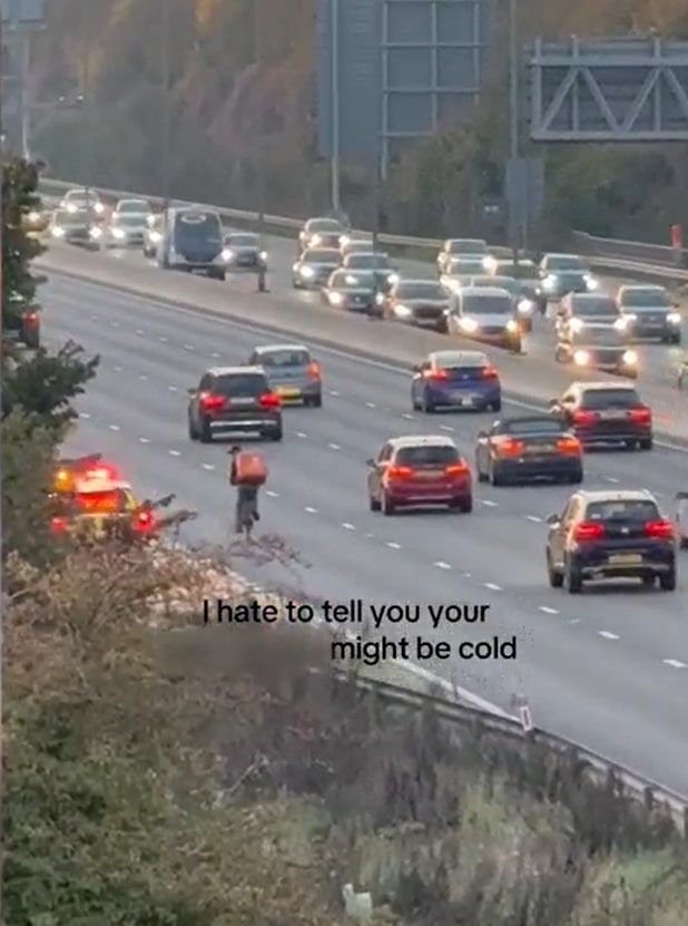 Food delivery cyclist on the M4 in rush hour traffic being stopped by police.