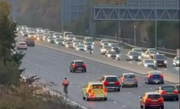 Head-scratching moment idiot food delivery cyclist pedals along the M4 in rush hour traffic before cops berate him