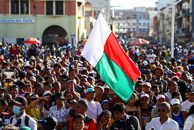 A protester waves his country's flag as demonstrators gather outside the town hall in Antananarivo