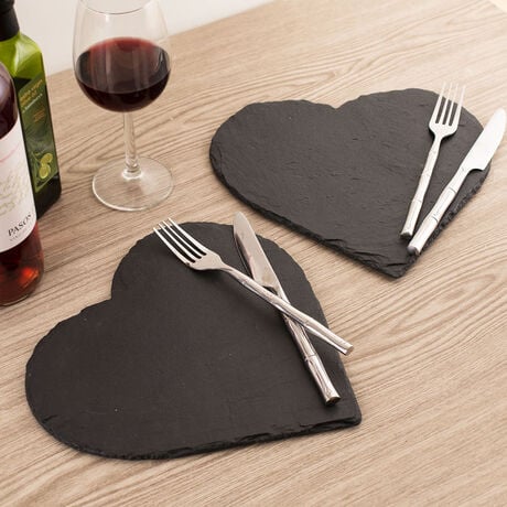 Two heart-shaped slate platters with cutlery, a bottle of wine, and a bottle of olive oil.