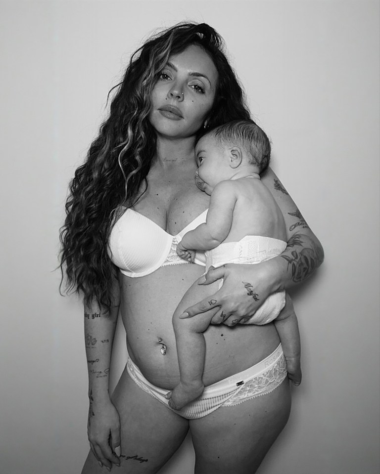 A mother in a white bra and underwear holds a baby.