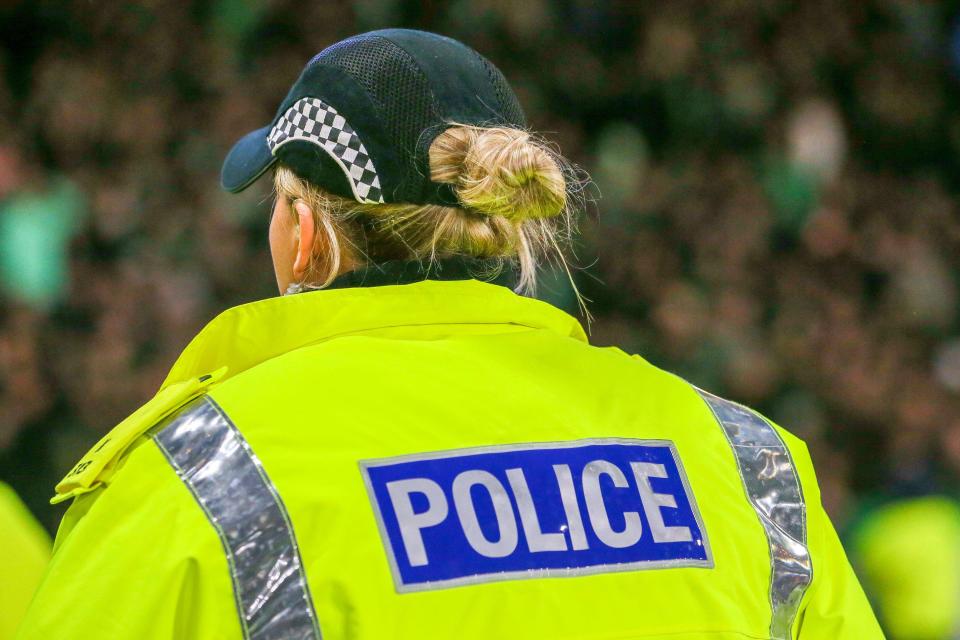 Female police officer from Police Scotland watching Celtic Football Club fans.