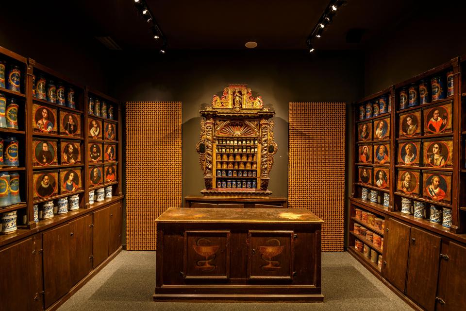 The historical Esteva pharmacy in Llívia, featuring the old pharmacy and a wooden counter with a painted bowl and snake.