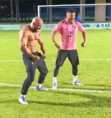 Two men dancing on a soccer field.