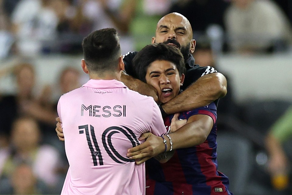 Yassine Chueko, Lionel Messi's bodyguard, pulling a fan away from Messi on the soccer field.