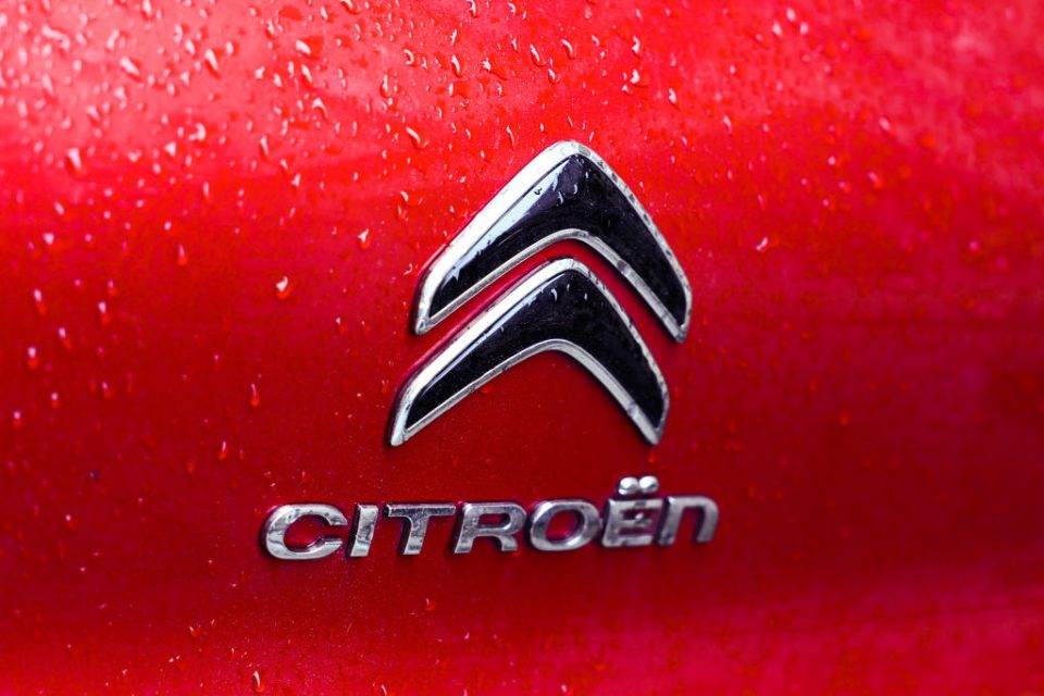 Close-up of the Citroen car logo and wordmark on a wet red surface.