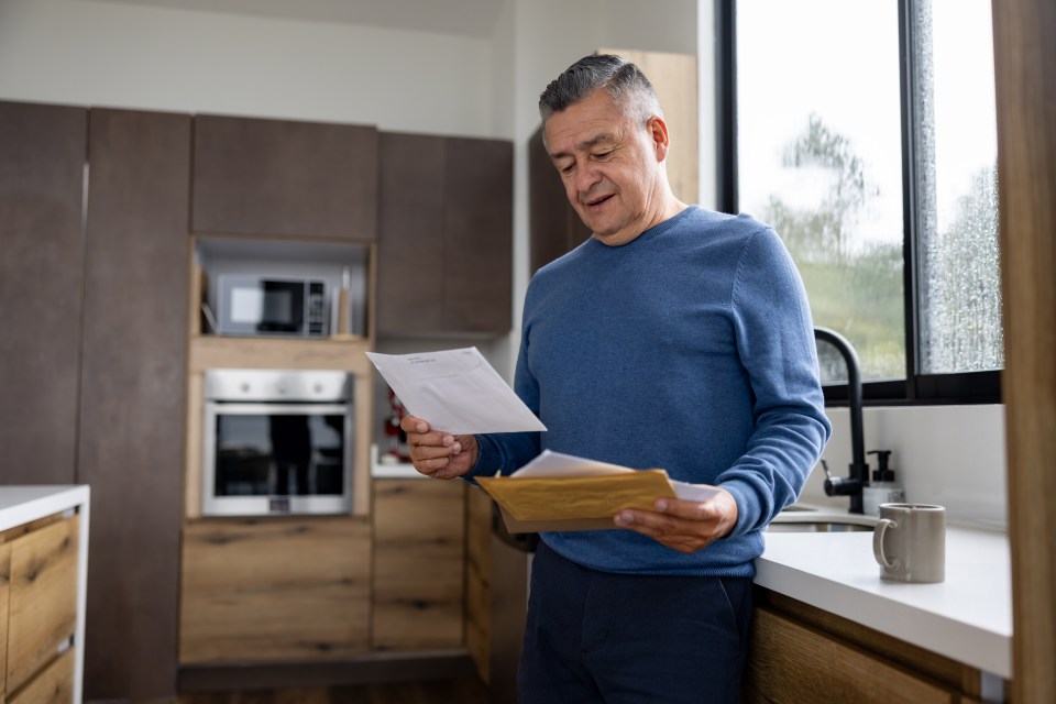 Mature Latin American man in his kitchen checking his mail.
