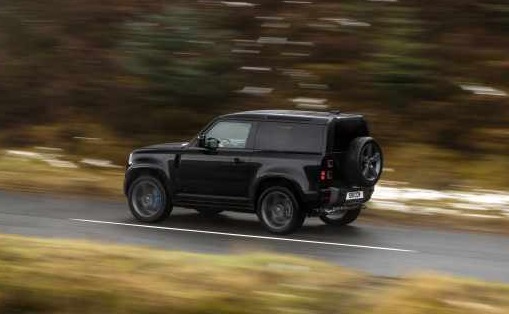 Black Land Rover Defender driving on a road.