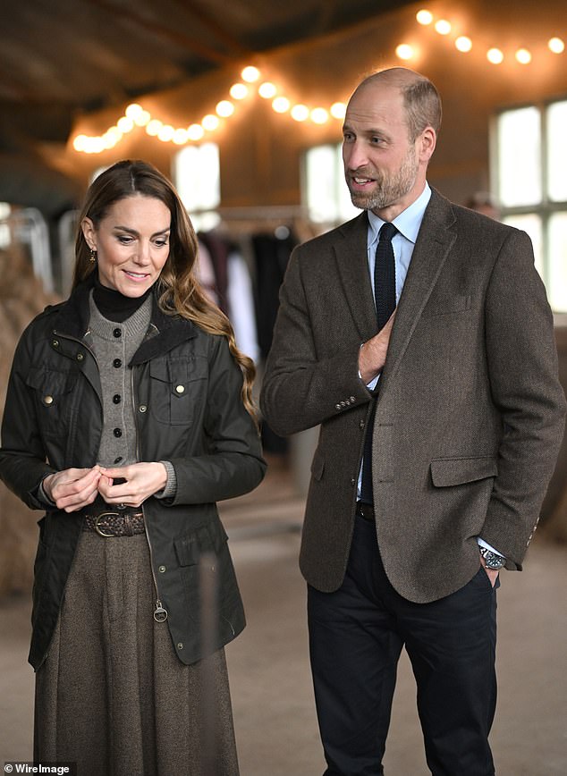 Kate and William, dressed in a brown blazer, speak to staff during their visit to the farm on Tuesday