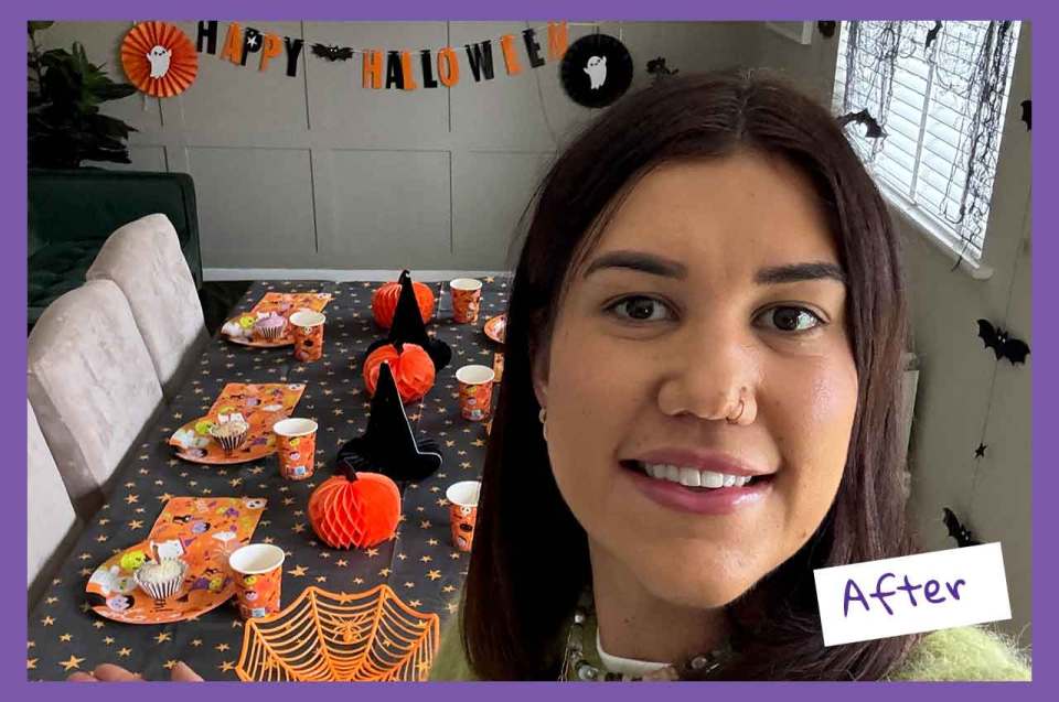 Woman smiling at a Halloween party setup with a table covered in themed decorations.
