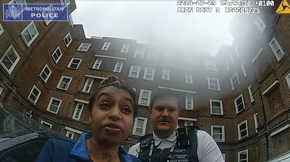 Police bodycam footage showing a woman and a police officer standing in front of an apartment building.