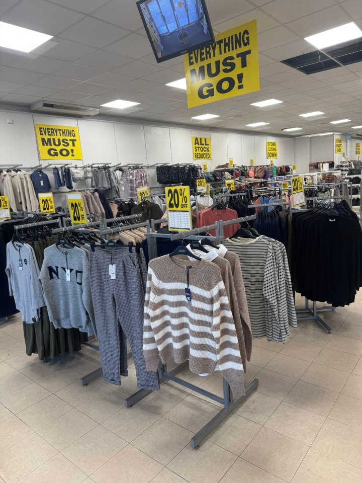 Clothing racks with "EVERYTHING MUST GO!" and "20% OFF" signs in a store.