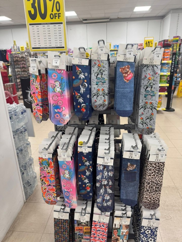 Display of socks with various patterns, including unicorns, astronauts, and cartoon characters, with a "30% OFF" sign above.