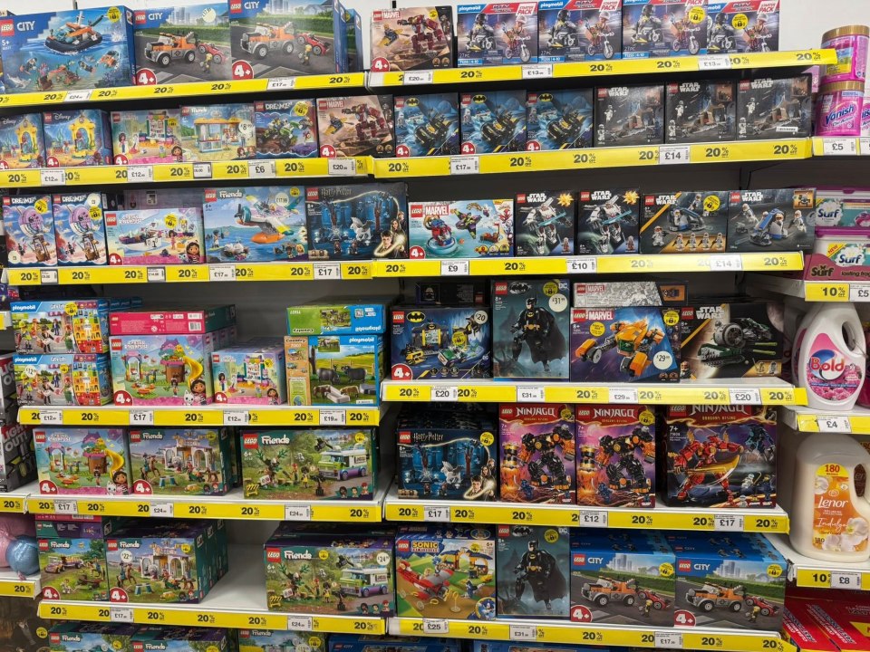 Shelves filled with various LEGO sets, including Marvel, Star Wars, Harry Potter, Friends, City, and Ninjago, all with "20% off" sales tags.