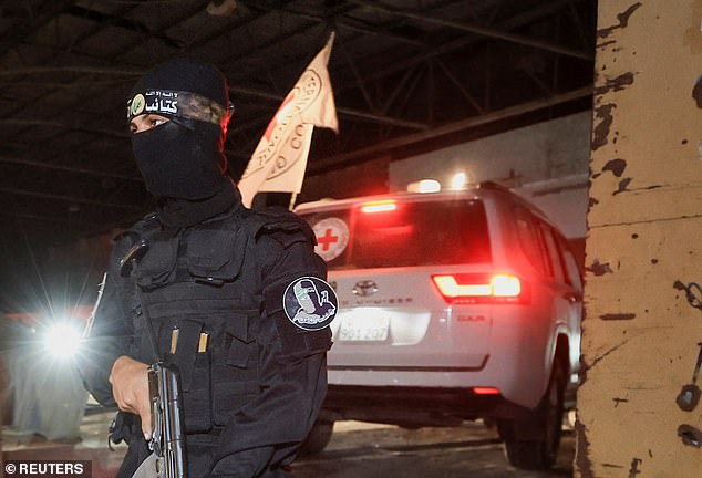An armed Hamas militant stands guard as a Red Cross vehicle arrives to receive from Hamas militants the bodies of deceased Israeli hostages