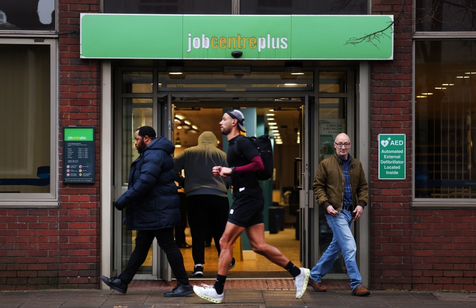 Pedestrians walk past a Jobcentre Plus in London, Britain.