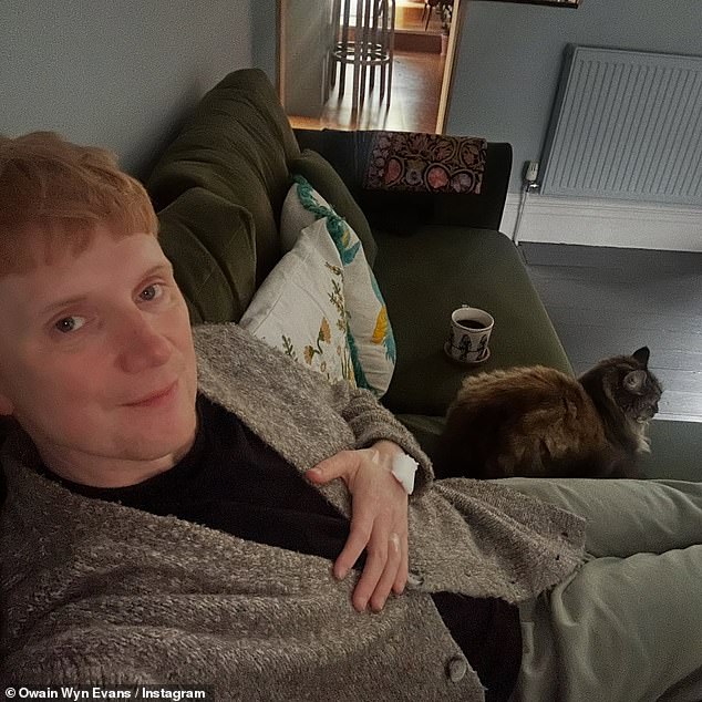 In his post, Owain shared a selfie of himself in his hospital gown in bed on the ward, and a second of him recuperating at home with his rescue cat Franny by his side