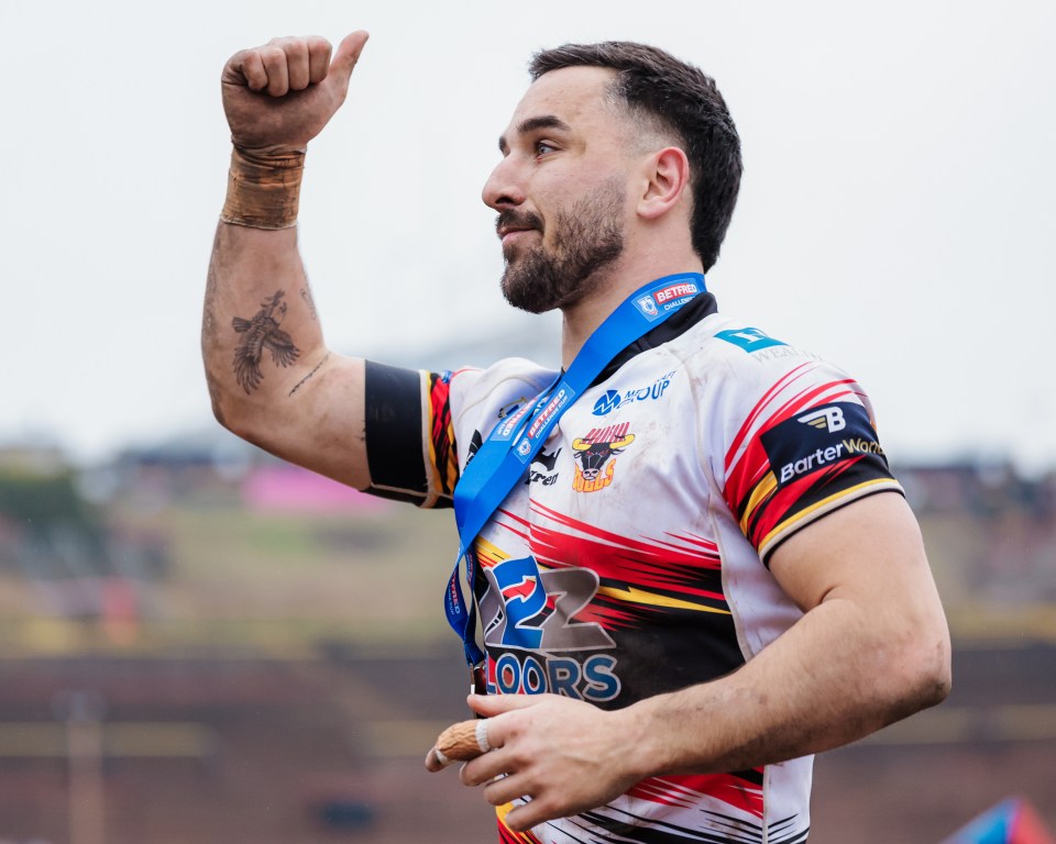 A rugby player from Bradford Bulls, wearing a Betfred Challenge Cup medal, pumps his fist.