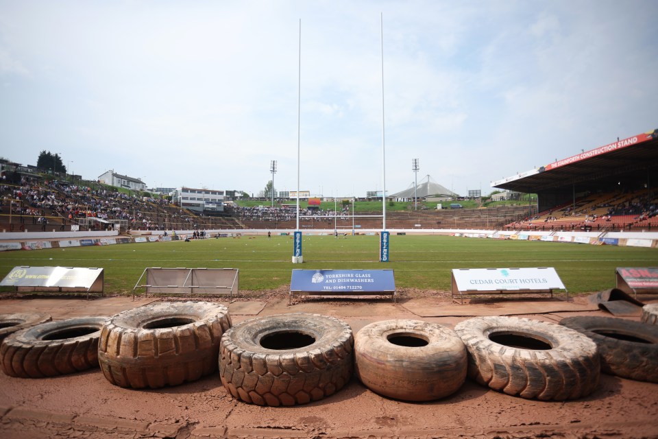 The Odsal Stadium, home to the Bradford Bulls rugby league team, with spectators in the stands, goal posts on the field, and advertising hoardings around the pitch.