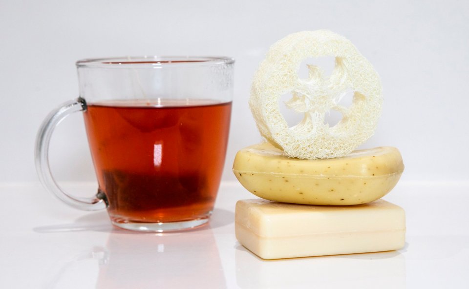 A glass of tea with two stacked bars of soap and a loofah.