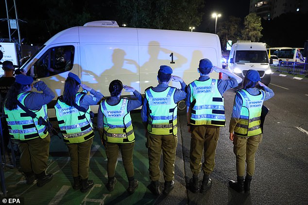 Israeli soldiers salute as a convoy carrying the two bodies passes