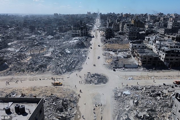 Pictured:  Palestinians walk in an intersection surrounded by buildings destroyed during two years of Israeli army bombardments in Gaza City