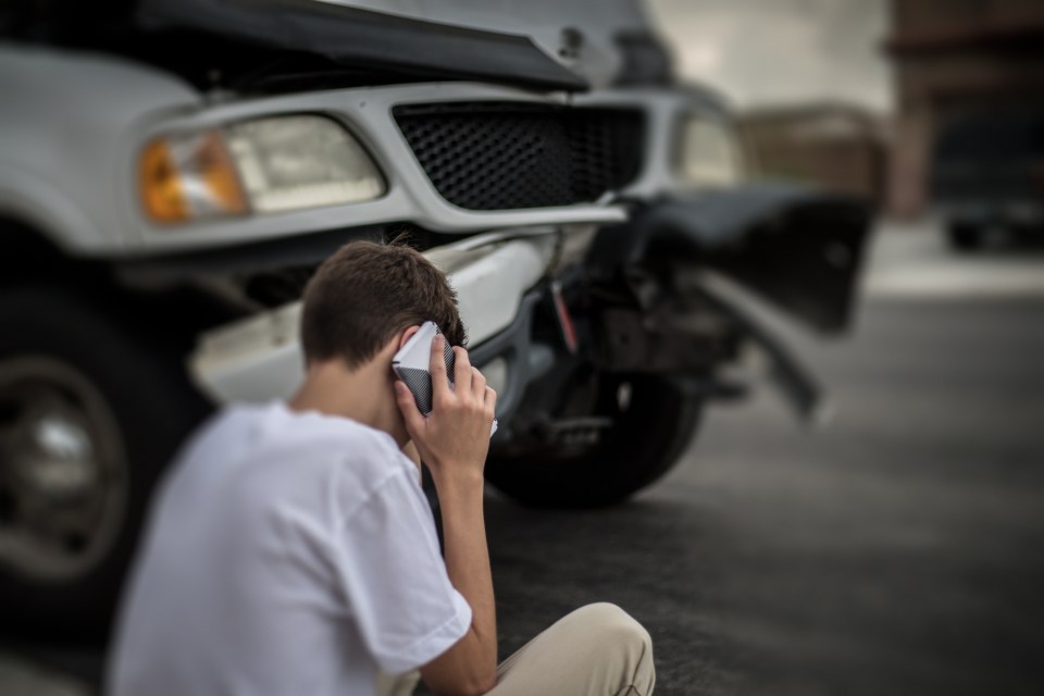Teenager on phone after car accident.