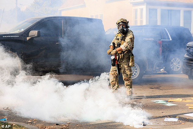 A government official readies to throw a gas canister in Chicago, Tuesday, October 14, 2025