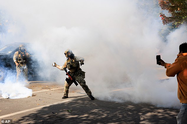 A government official throws a tear gas canister towards protesters in Chicago, Tuesday, October 14, 2025
