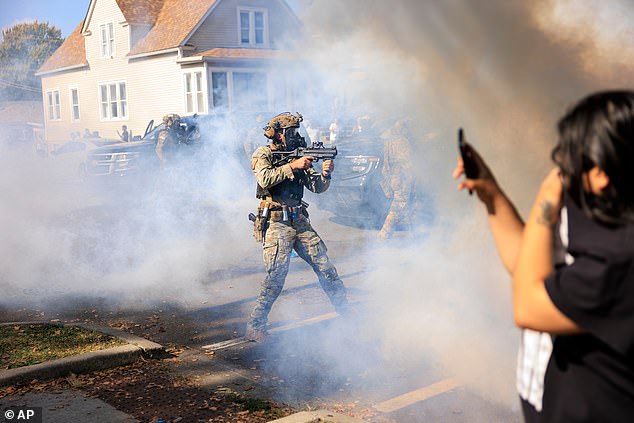 A U.S. Customs and Border Protection agent points a non-lethal weapon at protesters in East Side, Chicago, Tuesday, October 14, 2025