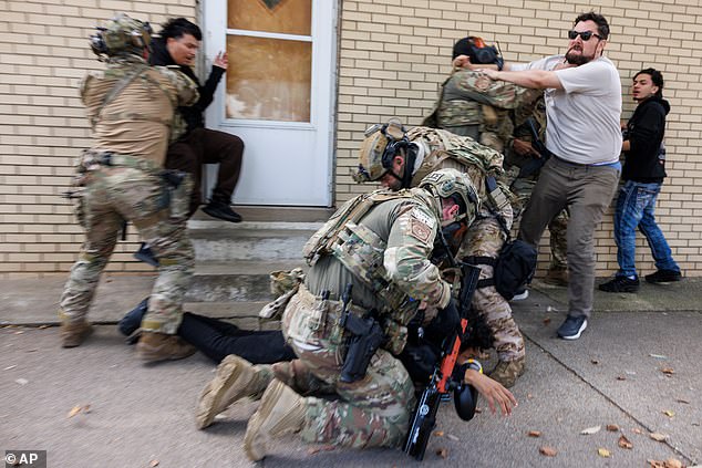 A detainee is taken back to official government vehicles during a protest in Chicago, Tuesday, October 14, 2025