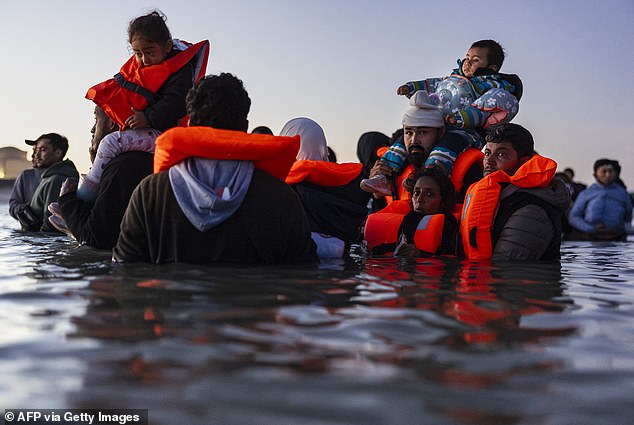 Migrants carrying children waiting to board a smuggler's boat in an attempt to cross the English Channel in September 2025. Being attacked for opposing mass illegal entries like this could lead to refuge in the US if the new proposals are given the green light