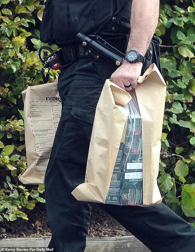 An officer carried out several boxes labelled High Pheasant cartridges - a type of hunting ammunition - and placed them in the boot of a marked police car