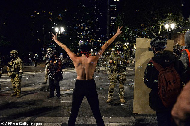 Pictured: A protester confronts authorities in Portland in 2020
