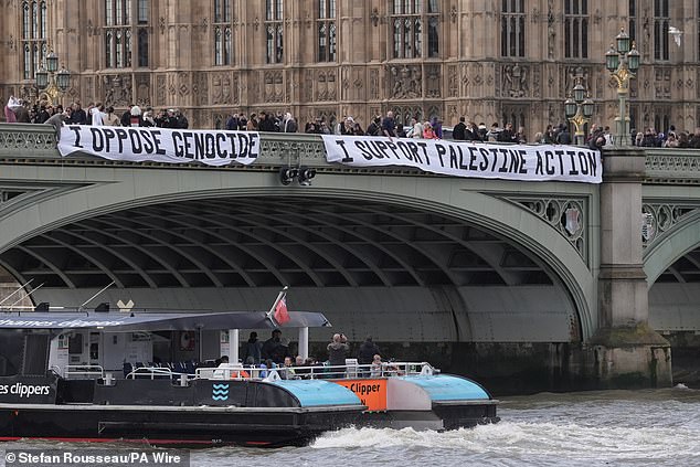 Protesters unfurl a banner on Westminster Bridge as part of a demonstration organised by Defend our Juries, in support of Palestine Action on October 4