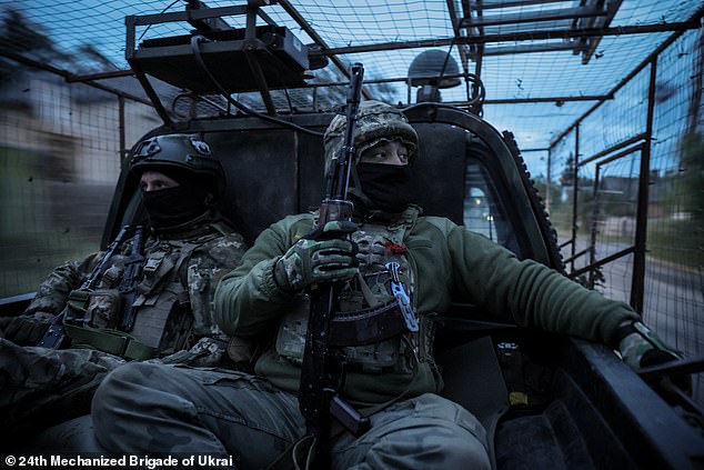 Ukrainian soldiers ride in the back of a car covered with an anti-drone mesh at an undisclosed location in the Donetsk region on September 19