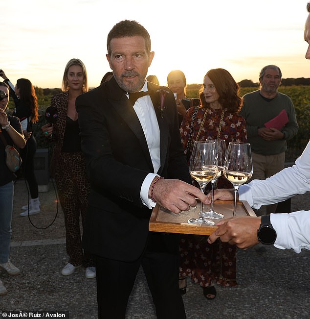 He mingled and cheerfully conversed with people nearby while sipping on a refreshing glass of white wine