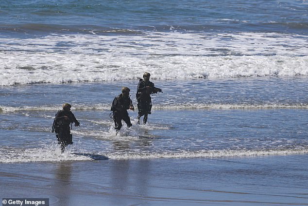 A team of U.S. Navy SEALS emerge onto the beach during the America's Marines 250 event at Camp Pendleton's Red Beach