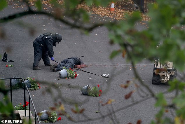 Al-Shamie was shot dead by police following the attack outside a synagogue in Manchester. Pictured: An Army bomb disposal expert and a remote-controlled robot check his body