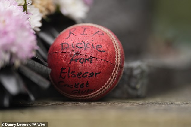 Fans left cricket balls among the floral tributes to the player by his bronze statue on Sunday
