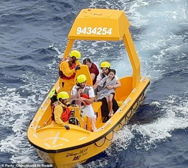 Pictured: The ship's crew taking the father and daughter back to the Dream after plucking them from the ocean. The girl is sitting on the knee of the ship's doctor being examined