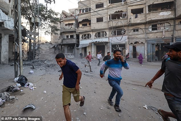 People run for cover following an Israeli strike that targeted a building in the Bureij camp for Palestinian refugees in the central Gaza Strip on October 19, 2025