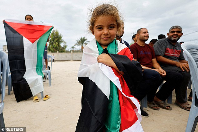 A girl holds a Palestinian flag in the central Gaza Strip after U.S. President Donald Trump announced that Israel and Hamas agreed on the first phase of a ceasefire