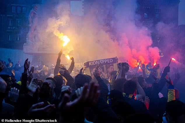 Maccabi Tel Aviv supporters light flares in Amsterdam ahead of the club's game against Ajax last year while holding up a poster depicting the hostages kidnapped by Hamas