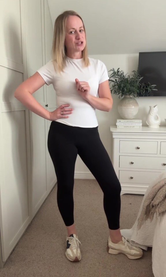 Woman wearing a white shirt and black leggings with sneakers.