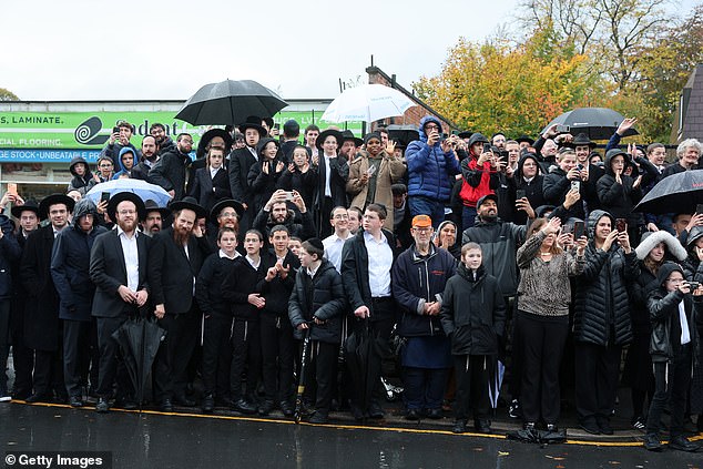 Members of the public wait to see King Charles III during his visit to the synagogue today