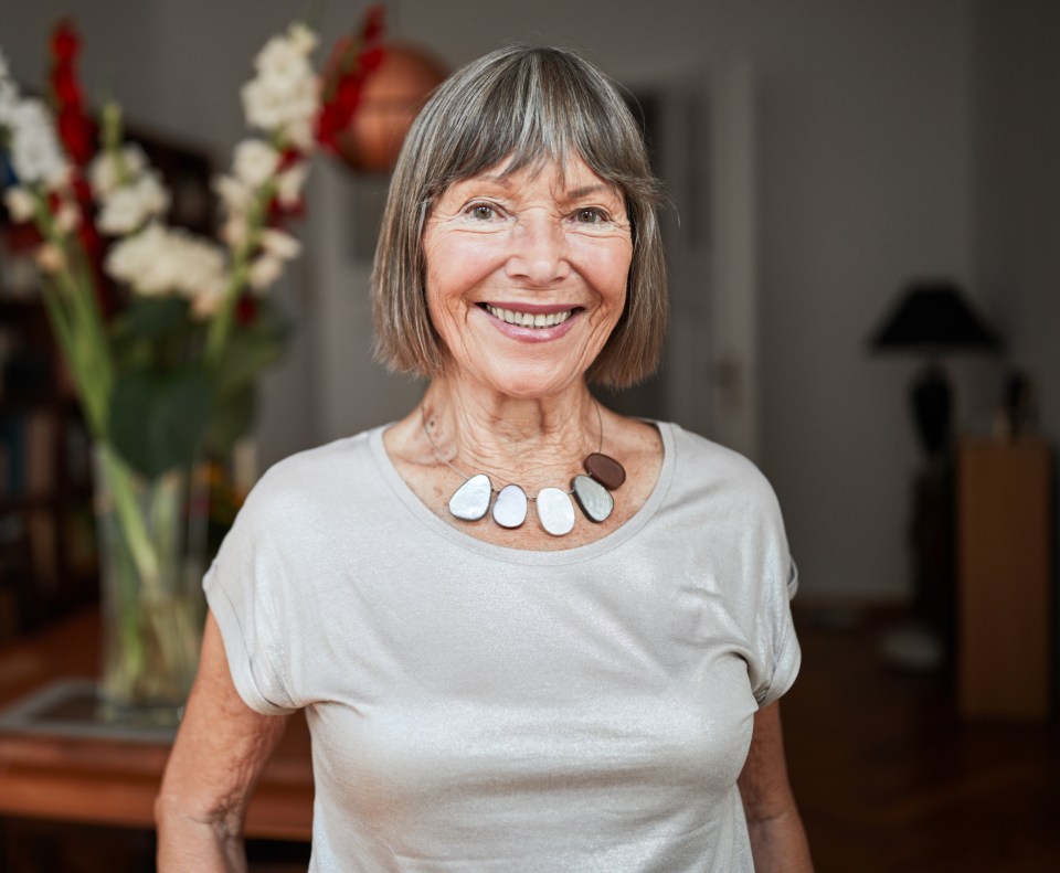 Portrait of a smiling senior woman with short gray hair and a necklace.