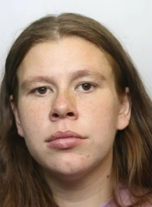 A headshot of a young woman with long, light brown hair, light brown eyes, a neutral expression, and freckles across her nose and cheeks.