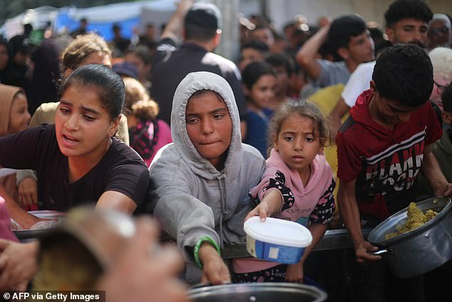 Palestinian children gather to receive food portions from a charity kitchen in the Nuseirat refugee camp, located in the central Gaza Strip, on Tuesday