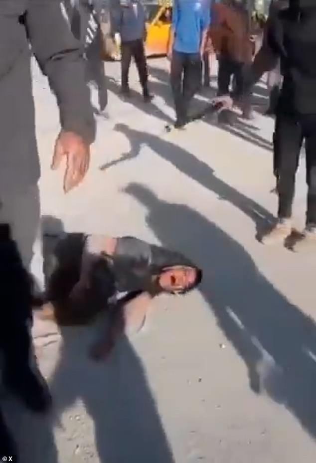 What appears to be a younger civilian can be seen crying out in pain as they are beaten by the masked men with iron bars